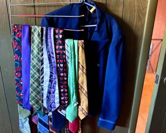 Collection of vintage neckties hanging on a multi-tier wire hanger alongside a blue jacket mounted on wood paneling.