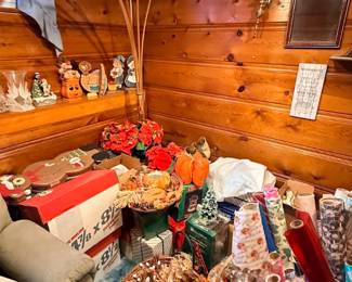 Vintage mid-century brass arch floor lamp with multiple arms, positioned over an assortment of seasonal holiday decorations, gift wrap rolls, and boxed items.