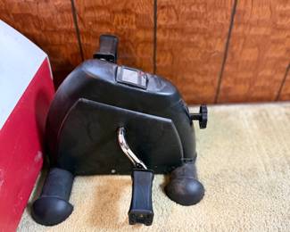 Black compact mini exercise bike pedal exerciser with digital display, showing light wear.