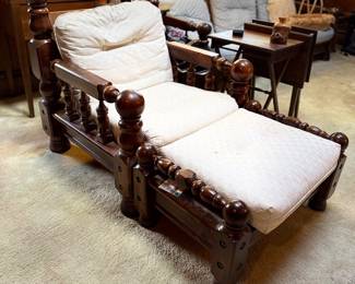 Vintage dark wood spindle-back chaise lounge with matching ottoman and cream tufted cushions.