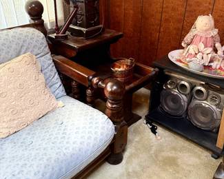 Vintage heavy dark wood armchair with light blue patterned cushions alongside a matching dark wood end table holding a lamp, miniature decorative harp, and copper bucket.
