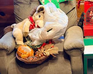 Plush stuffed horse, decorative pumpkin basket, and assorted holiday decor resting on a gray plush recliner chair.