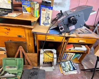 Vintage benchtop planer tool resting on a wooden desk alongside boxed model car kits and a Dremel drill press box.