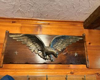 Vintage brass or cast metal American eagle wall plaque mounted on a dark wood board with star accents.