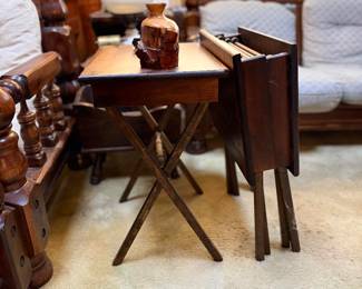 Set of vintage dark wood folding TV tray tables with a matching storage rack stand, featuring an open table with a live-edge wooden decorative vase.