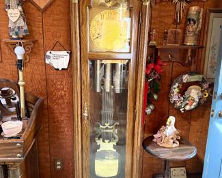 Vintage oak grandfather clock with ornate brass pendulum, moon phase dial, and glass door case.