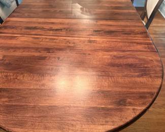 Acacia Wood oval dining table, pedastal base, with two leaves. 48" round without leaves.