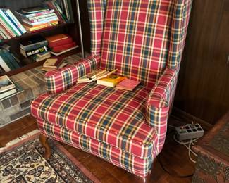 Red plaid wingback chair with bookcase and Oriental-style rug