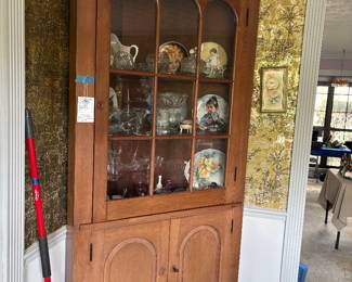 Wood corner cupboard with glass doors and dishware