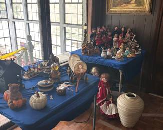 Sunroom tables of dolls, baskets and pottery with framed art