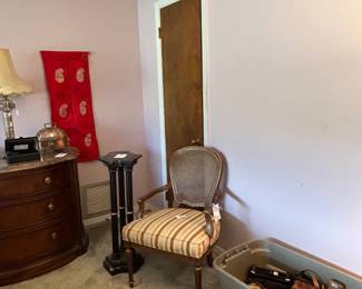 Bedroom with striped armchair, nightstand and bin of belts