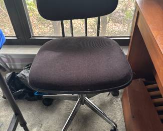 Black upholstered rolling office chair by wood desk