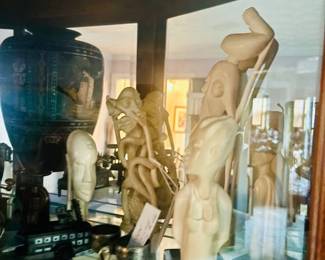 Lighted curio with carved white figural sculptures and black vase