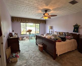 Primary bedroom with sleigh bed and tables of clothing