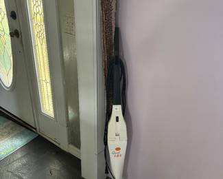 Stick vacuum by front entry door