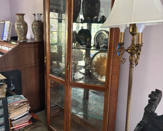 Lighted curio cabinet with pottery and brass floor lamp