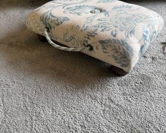 Upholstered floral footstool on bedroom carpet