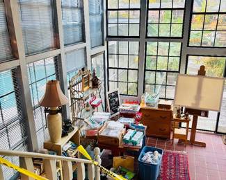 Sunroom view with easel, lamps and tables of art supplies