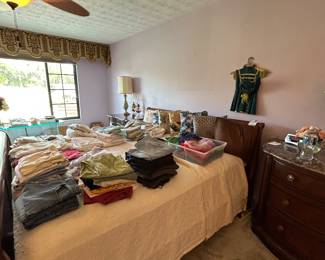 Bedroom bed covered with sweaters and folded clothing