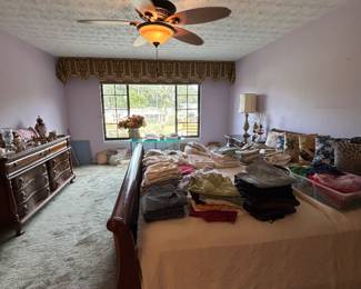 Primary bedroom with wood bed, dresser and folded clothing