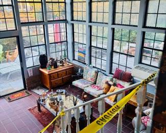 Sunroom with cushioned settees, wood dresser and red tile floor