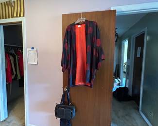 Bedroom doorway with hanging women's clothing and handbag