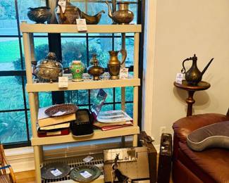 Shelf of brass and copper ewers and pitchers with Persian-style rug