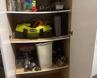 Sturdy white double-door storage cabinet featuring 5 spacious shelves. Currently used for tool and hardware storage. Includes a premium lime green/black Ryobi canvas tool tote bag, automotive detailing kits, jars of sorted screws/nails, and multiple replacement brass doorknob hardware sets