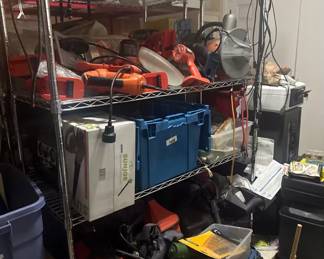 electric bench grinder, heat guns, extension cords, a brand-new Sun Joe boxed tool/appliance, heavy-wall storage bins, and various hardware accessories. 