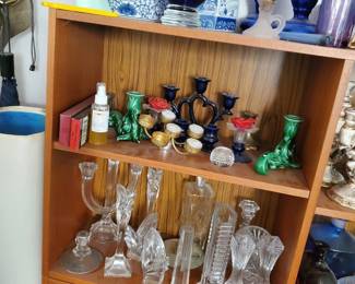 A high-quality collection of decorative pottery and glassware. Features a large, traditional blue and white Chinese porcelain ginger jar with a wooden lid, a matching blue and white porcelain rectangular box vase, a prominent rich cobalt blue art glass urn vase, tall cobalt blue candlestick pillars, and jade-green ceramic stylized figurines