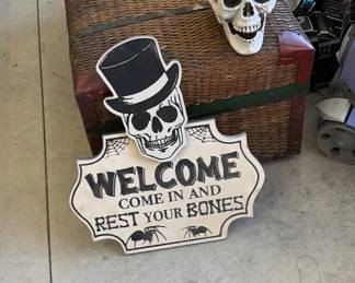 Halloween "Come In and Rest Your Bones" welcome sign, skull, and wicker trunk.