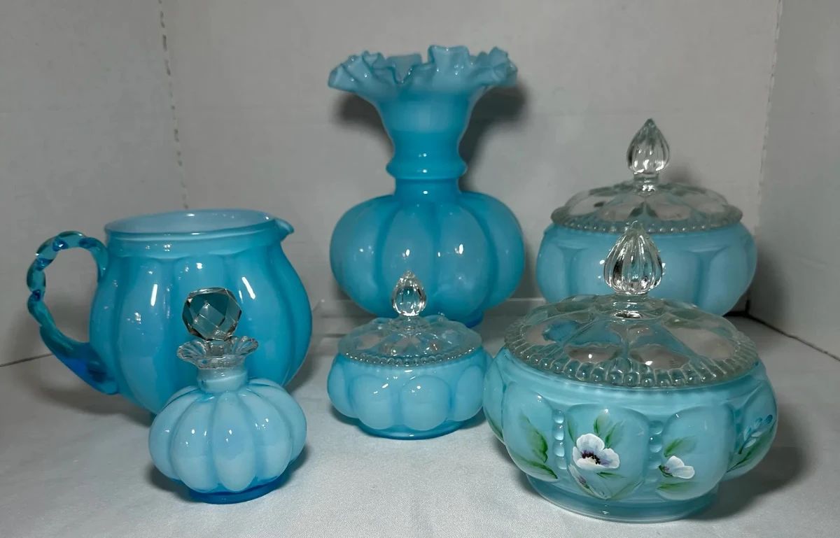 Fenton Blue Overlay Hand Painted Pitcher, Vase, Perfume Bottle and Covered Jars - A Fenton blue overlay pitcher, a ruffled vase, a stoppered perfume bottle, and two covered jars with clear finials, including one with hand painted flowers. A good lot for Fenton collectors.
