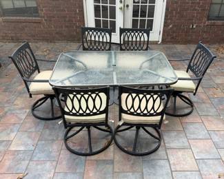Patio Dining Set with Glass Top Table and 6 Swivel Chairs - An outdoor dining set with a glass top table and six metal swivel chairs with cream cushions. A good set for a patio or deck.