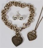 Lot#13, TIFFANY & CO. STERLING SILVER NECKLACE, BRACELET AND EARRINGS, 3 PCS.includes a heart shape Sterling silver pendant, 7/8" H., stamped: "Please Return To Tiffany & Co New York 925" suspended from a Sterling silver small link chain, 17" L. One ring link bracelet, 7 1/4" L., with heart shape charm inscribed: "925 Please Return To Tiffany & Co New York" plus pair of Sterling silver spherical post earrings, (no backs), etched: "Tiffany & Co." on each; tw 1.6 tr. Oz.