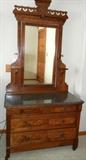 Lot#82, ANTIQUE AMERICAN WALNUT DRESSER H 90" L 42" D 21"Dresser having black marble top, tilt mirror, three drawers with round circular pull handles. on casters; Dresser, H 90", L 42", D 21". All on casters.