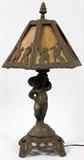 Lot#317, SLAG GLASS AND CAST GILT METAL TABLE LAMP, C1930, H 24", DIA 12"having a hexagonal shape with flat slag glass panels with pierced cast gilt metal frame with gargoyles, mounted on a gilt cast metal shaft depicting a putti supported on a pierced design square footed base;