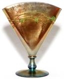 Lot#1009, STEUBEN DECORATED GOLD AURENE GLASS FAN VASE, H 8 1/2", W 6 3/4"Iridescent gold fan-form body with vine pattern in green, on an iridescent base of gold and blue.  Signed "Steuben Aurene" at the rim with an illegible number, possibly 6297 (see additional photo).  Early 20th century.  Reference: "The Glass of Frederick Carder", Paul V. Gardner, copyright 1971, Crown Publishers, New York, catalog line number 6297 (p.280).
