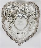 Lot#1166, GORHAM STERLING SWEETMEAT BOWL, 1896, L 9"Heart-form sterling silver bowl with repousse bowknot and scrolls, reticulate sides, and raised on three ball feet; stamped at the underside with trademark, number 4312, and date mark for 1896 (see additional photo).  Measures H.2" x 9 1/2" x 8".  Weighs approximately 8.2 troy oz.