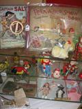 Small vintage and antique toys, books etc. are at table in living room inside cases