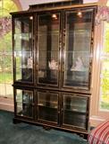 Oriental black lacquer china/curio cabinet from Plunketts.  Decorated with oriental scenes, flowers, foliage, etc.  Six beveled glass door, glass shelves, top and bottom section individually lighted.  Separates into two pieces.