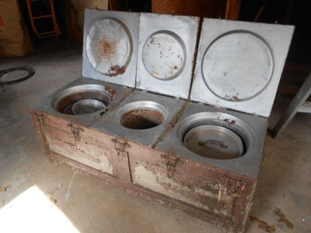 antique food service chest, side handles for carry/transport.  Insulated with straw, heated with hot stone shaped wheels  inserted underneath each serving pot. Lids fold down and have latches. 