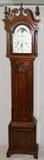 Lot#89, JOHN GODDARD MAHOGANY GRANDFATHER CLOCK, H 90", W 18", D 11.5"Federal Style, Manufactured by Sleigh, Holland, MI. A modern reproduction of the original Newport tall case clock manufactured by John Goddard in Newport, R.I. in 1760. Having an open pediment, vase and spiral carved capitols and stop fluted flame finials at the corners and center front; framed glass access door opening to a floral painted face, having a moon dial, second hand and date dial, three chimes and three key wind. Inscribed on face "John Goddard Newport"; carved wood block and shell access door opening to the pendulum flanked by fluted quarter columns; ogee bracket feet;