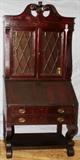 Lot#183, MAHOGANY SECRETARY DESK, C 1900, H 83", W 37"Empire style, slant front, opening to seven cubicles, flanked by small cabinet doors and above two above two narrow drawers all above two full width drawers, raised on scroll form legs with stretcher shelf at the bottom; two lattice framed glass doors opening to bookcase top with open pediment and finial. Has Key.