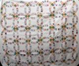 Lot#314, HAND MADE WEDDING RING QUILT CIRCA 1910 TO 1930 W 88" L 77"Handmade wedding ring quilt circa 1910 to 1930. Beautifully made, this quilt has been pieced together and quilted by hand. The trim along the edge was applied by machine but folded and finished by hand. The quilting is beautiful, the center of each ring is quilted in a pinwheel design.