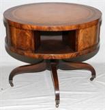 Lot#1235, MAHOGANY LIBRARY TABLE, H 29", DIA 36"Drum style mahogany table with inset tooled leather top, openings about for book storage, raised on four splay legs.