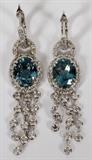 Lot#2172, 14 KT WHITE GOLD, AQUAMARINE & DIAMOND DANGLE EARRINGS,14kt white gold dangle earrings, with oval cut natural aquamarine gem centers, weighing 4.41 carats in total, surrounded by side diamonds, with three diamond chain dangles below. Total weight in diamonds is 1.50 carats, with a G-color, VS-2 clarity rating. The total weight of the earrings is 9.8gms.