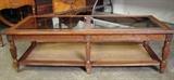Glass Top Coffee Table with Wood Frame, Carver Risers, and Strapped Bottom Shelf. Measures 51"l x 15"h. x 21"w.