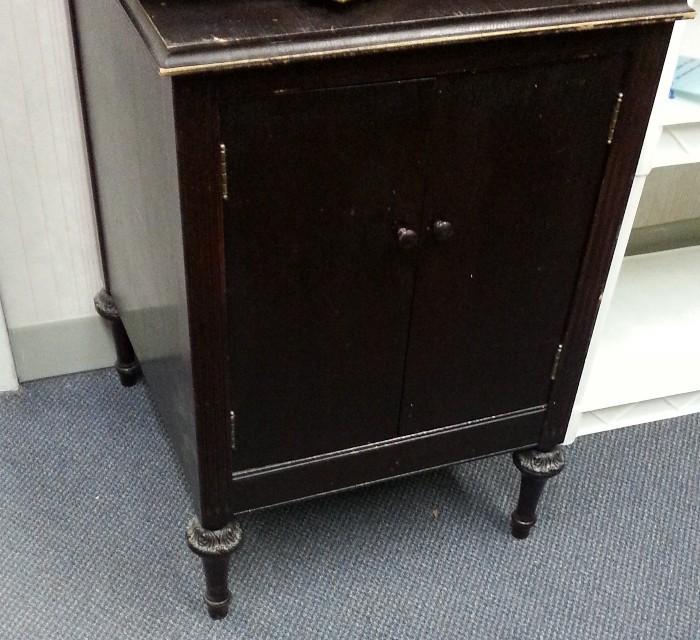 Dark stained solid wood small cabinet with doors on front for storage.  