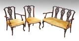 Lot 1024:  CHIPPENDALE MAHOGANY SETTEE & 2 CHAIRS: 3 richly carved pieces to include 1) Triple back settee with carved foliate scroll motif, shaped arms and supports, carved cabriole front legs. Mustard yellow upholstery. 35 1/2'' h. x 50 1/4'' x 25 1/2''. 2-3) Matching arm and side chair, arm measures 36'' h. x 27 3/4'' x 25 1/2''.