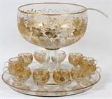 Lot#1009, VENETIAN ETCHED GLASS PUNCH BOWL WITH LADLE, TRAY & CUPS (12), C. 1920,Including 1 pedestal punch bowl, H.15", Dia.13", with 1 ladle, 1 tray, Dia.20", and 12 pedestal punch cups; etched grape vine motif overall with gold accents.  Fifteen pieces total.